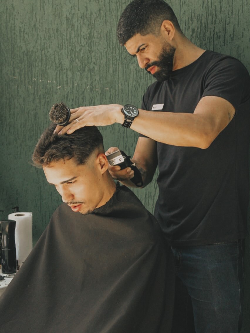Barbeiro da Barbearia do Mister finalizando um corte degradê